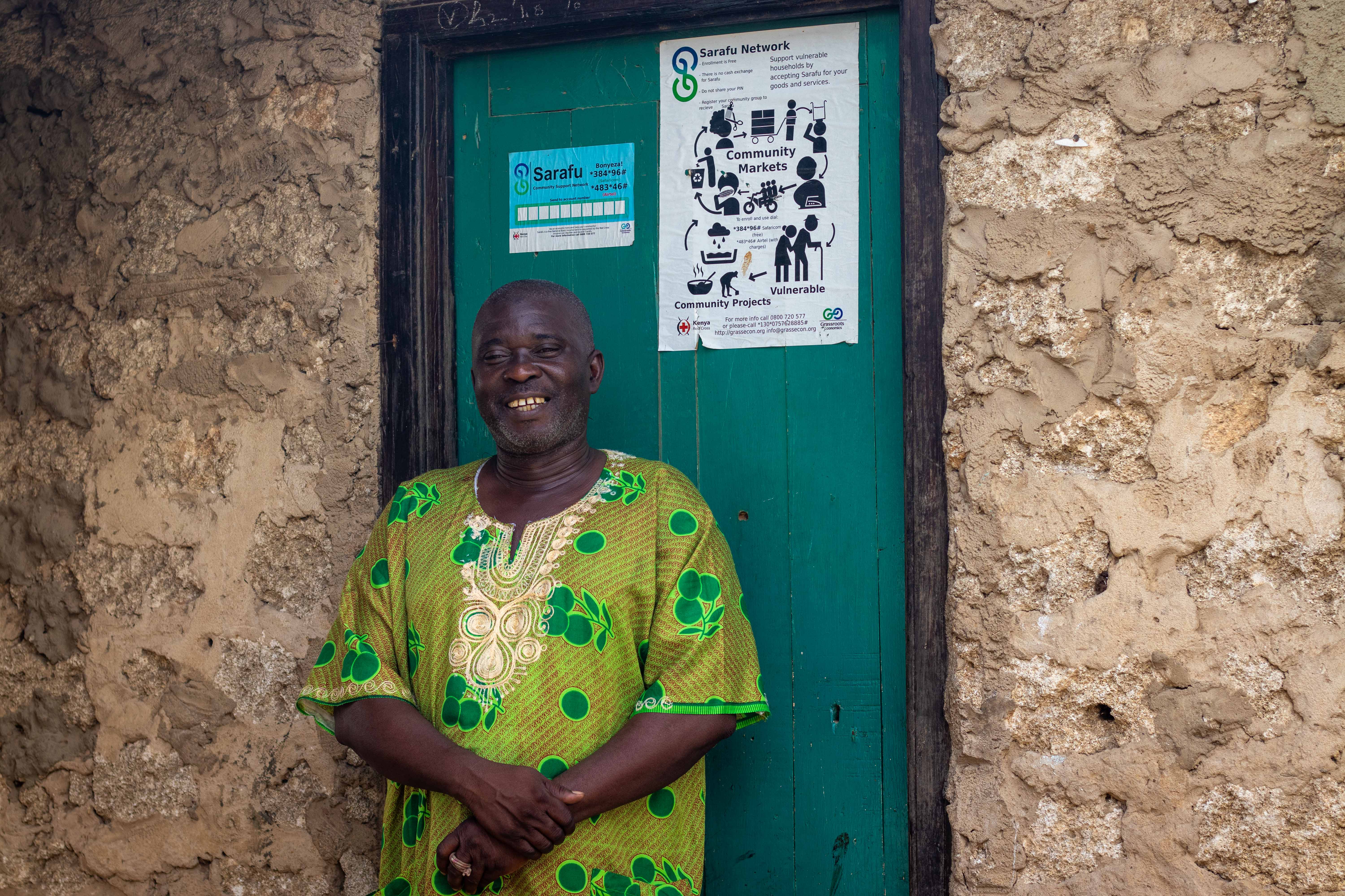 Community member standing in front of Sarafu Network information posters